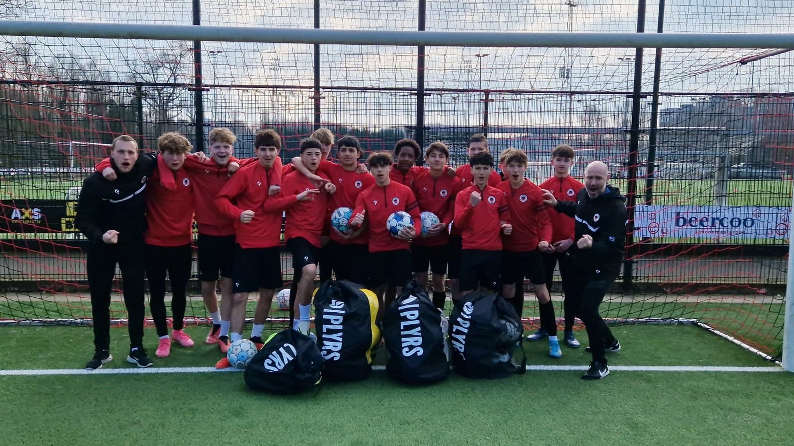A youth football team celebrating with PLYRS-branded kit bags after training